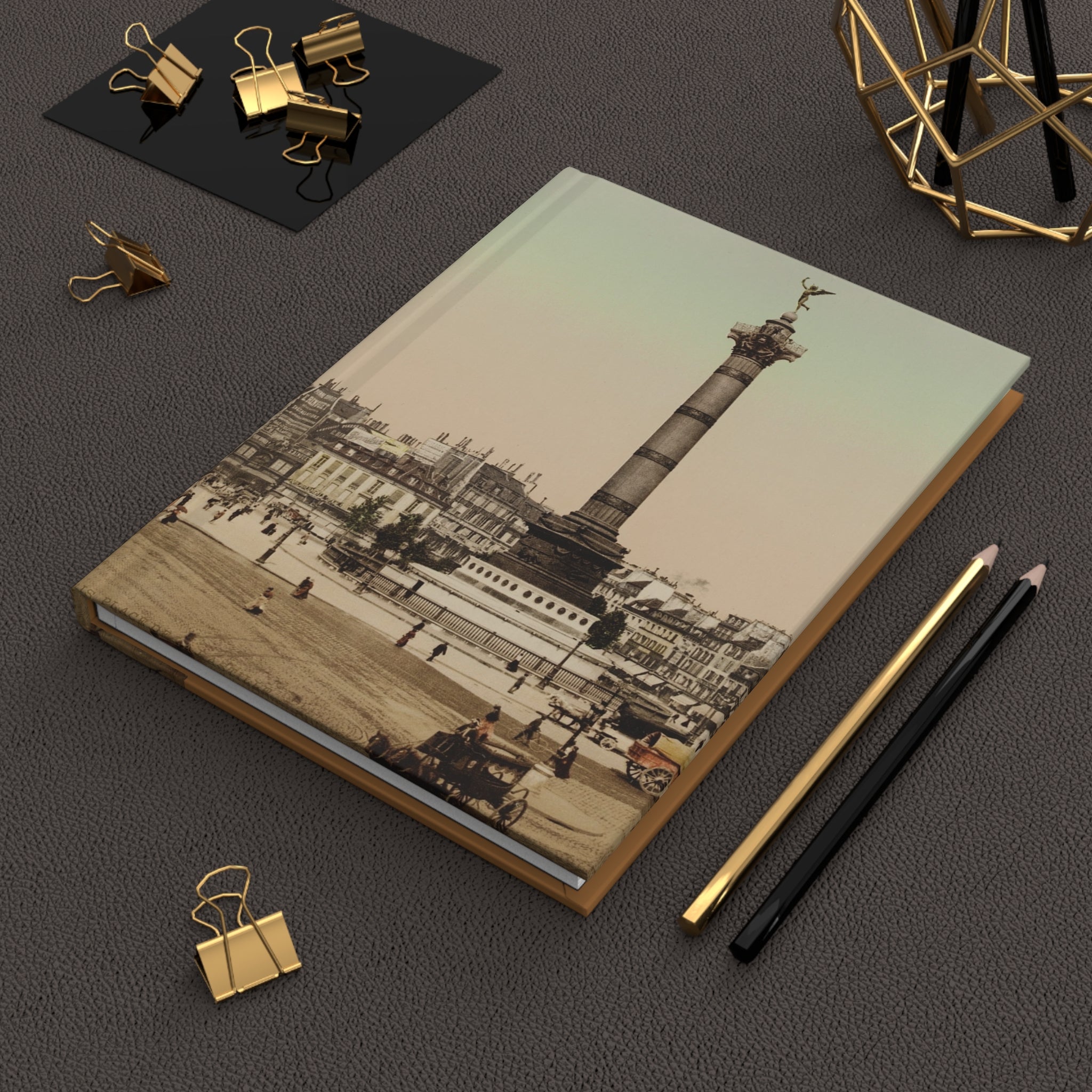 Notebook with vintage cityscape design on a dark surface with office supplies.