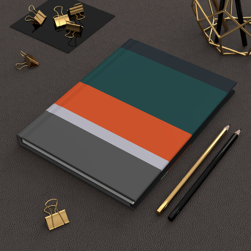 Notebook with a geometric design on a dark surface with office supplies.
