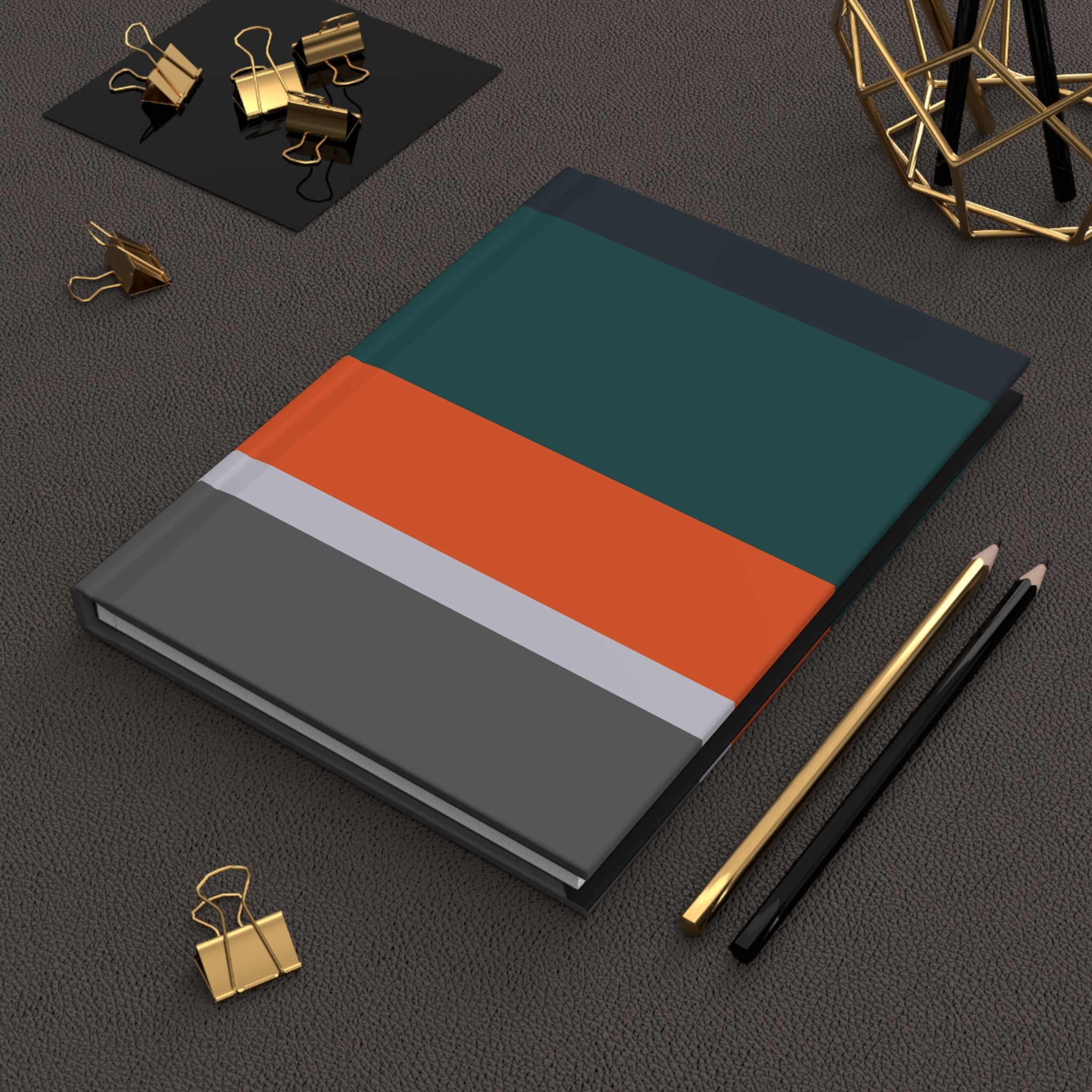 Notebook with a geometric design on a dark surface with office supplies.