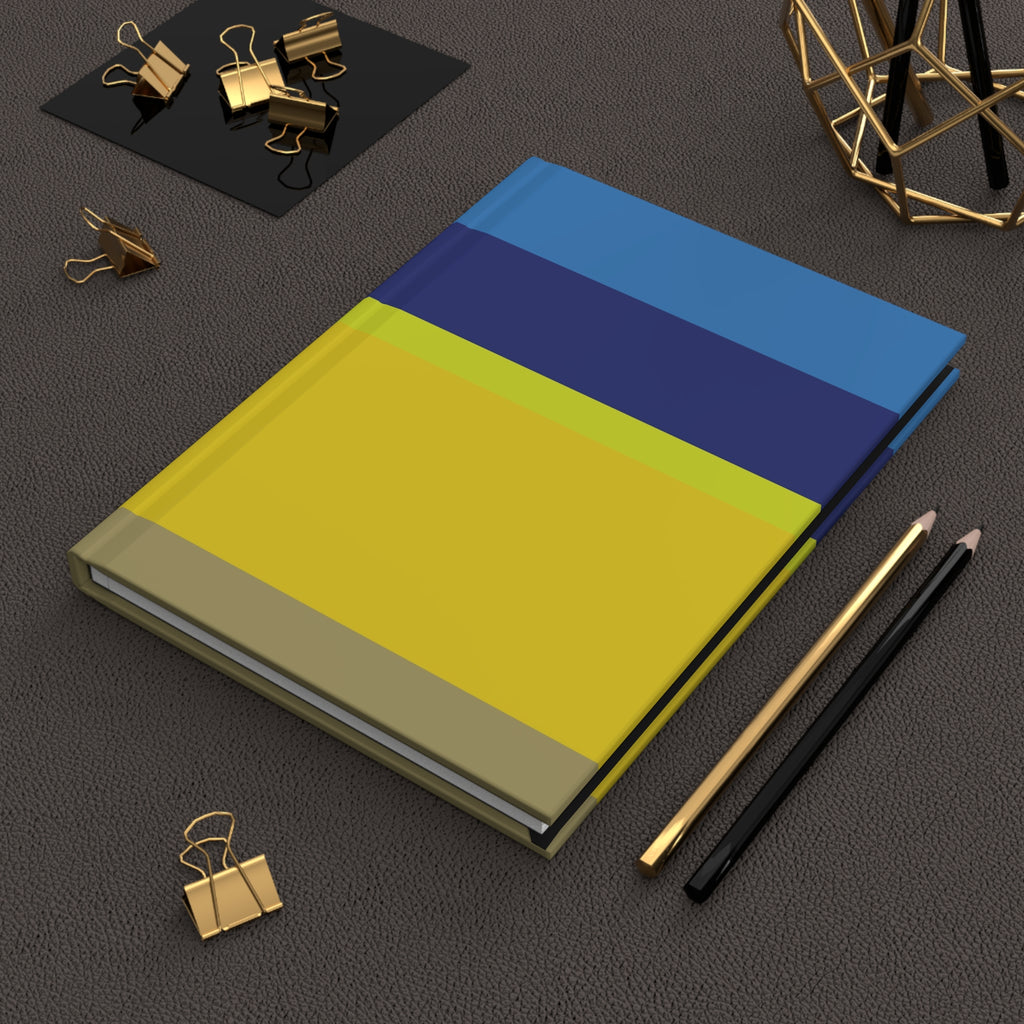 Notebook with blue and yellow cover on a dark surface with office supplies.