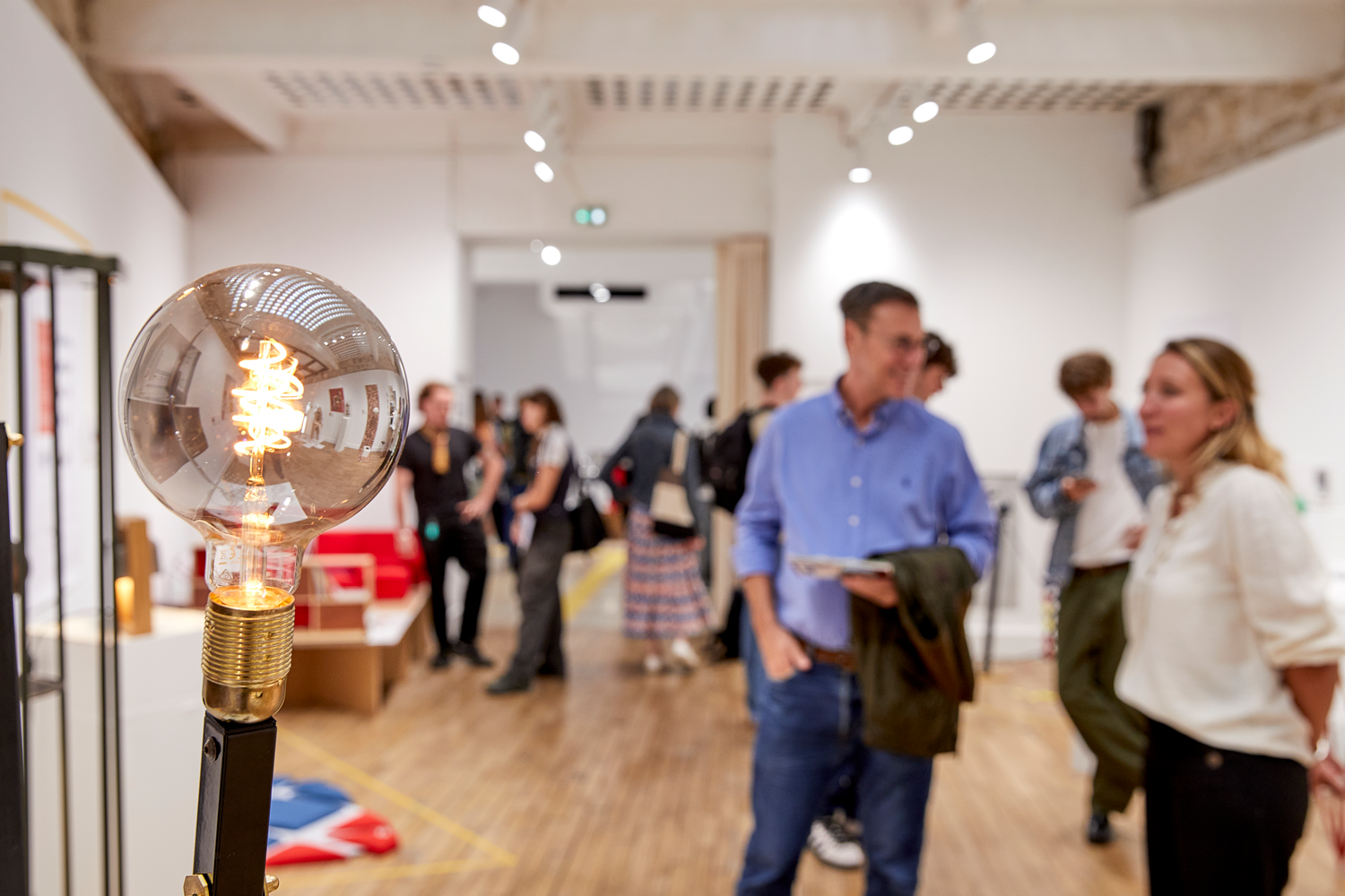 People walking through a modern indoor space with a large decorative light bulb.