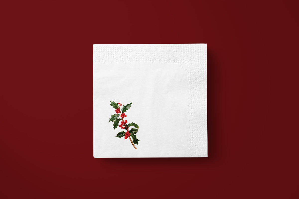 Noël Holly paper napkins on a deep red ground — a single napkin laid flat
