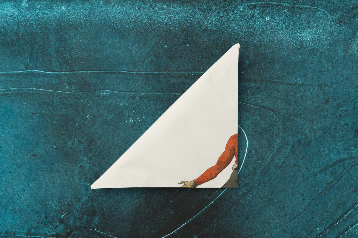 Noël L'Aplomb paper napkin on skating-rink ice — folded into a triangle