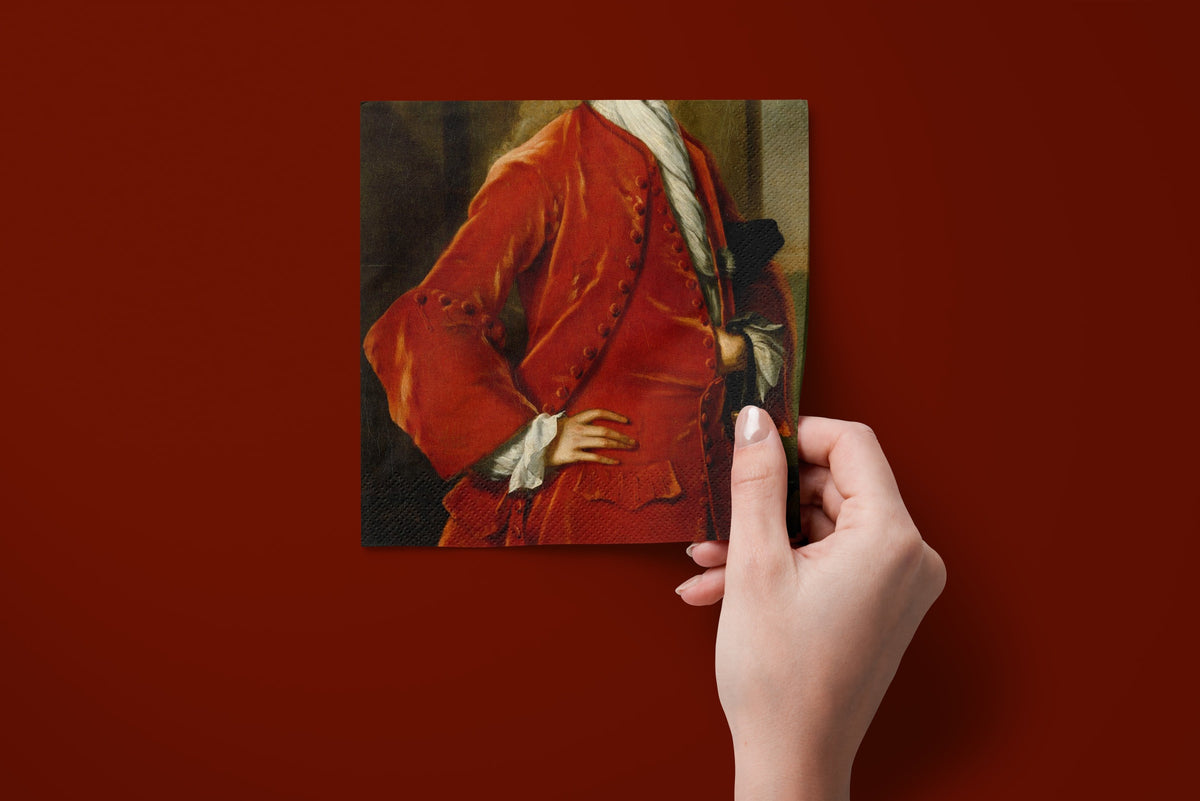 Noël L'Habit Rouge paper napkins on a deep red ground — a napkin held in hand