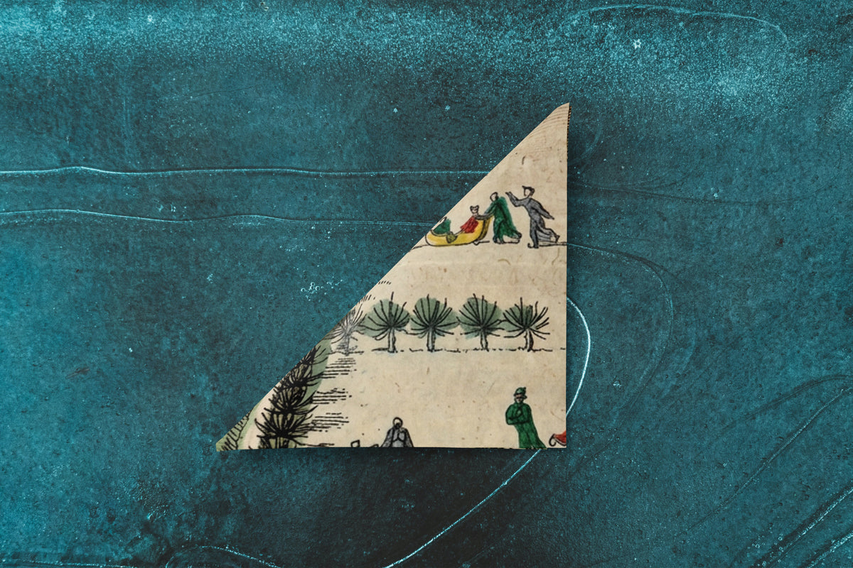 Noël La Patinoire paper napkin on skating-rink ice — folded into a triangle