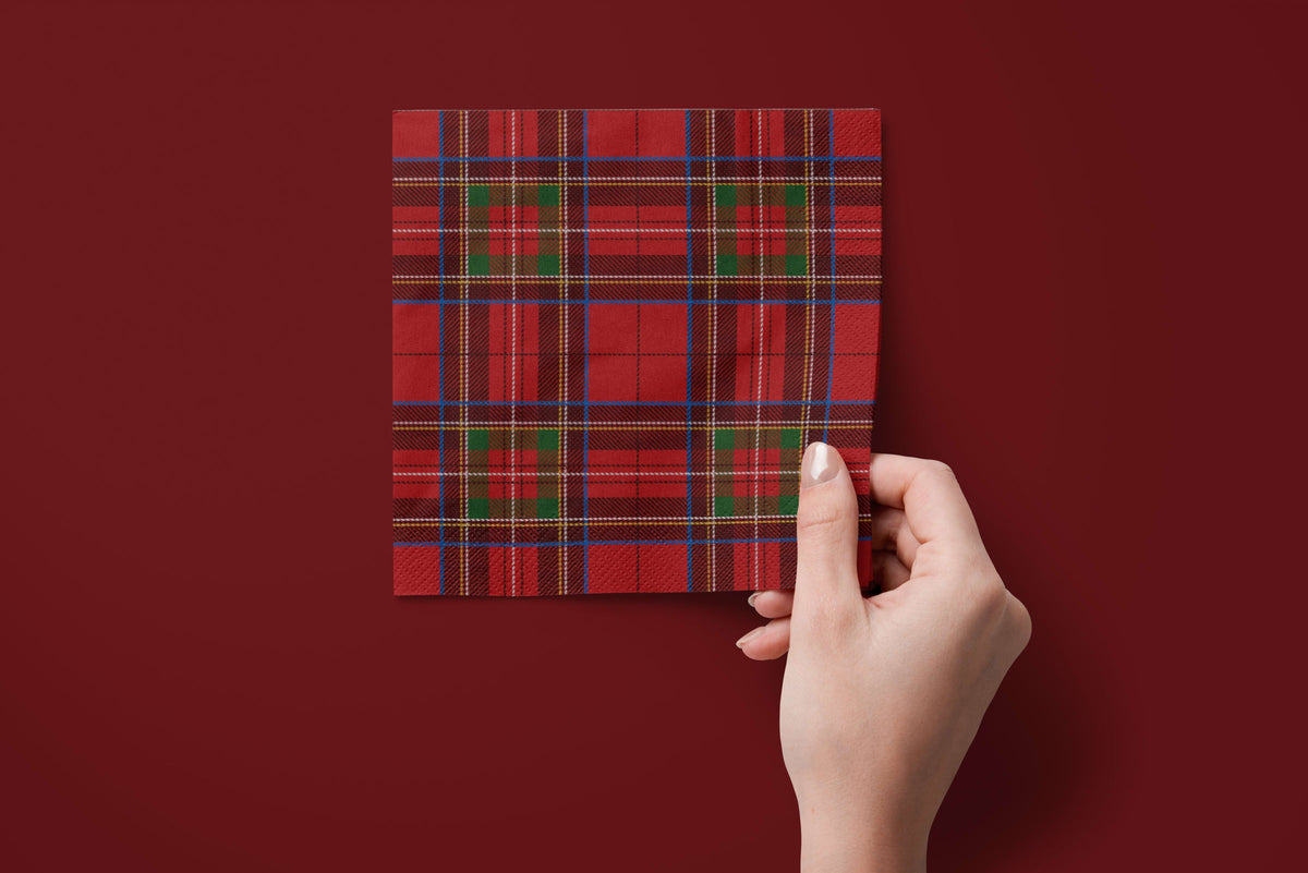 Noël Le Tartan paper napkins on a deep red ground — a napkin held in hand
