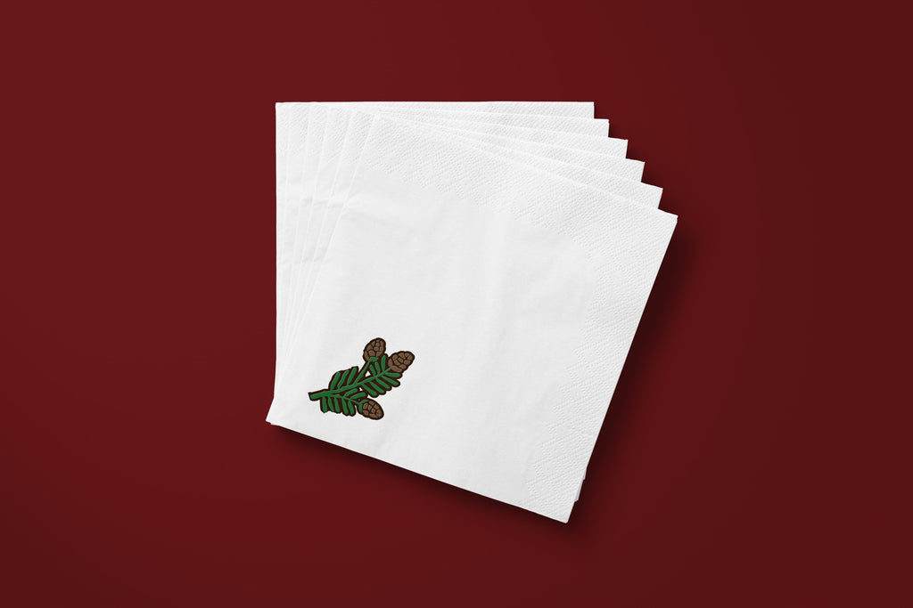 Noël Mini Pinecone paper napkins on a deep red ground — a fanned stack