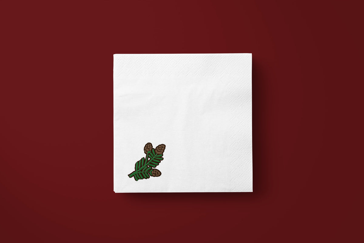 Noël Mini Pinecone paper napkins on a deep red ground — a single napkin laid flat