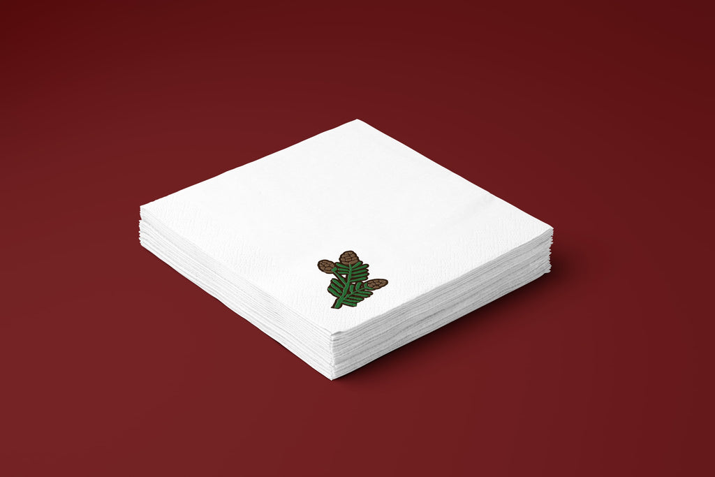 Noël Mini Pinecone paper napkins on a deep red ground — a stack of napkins