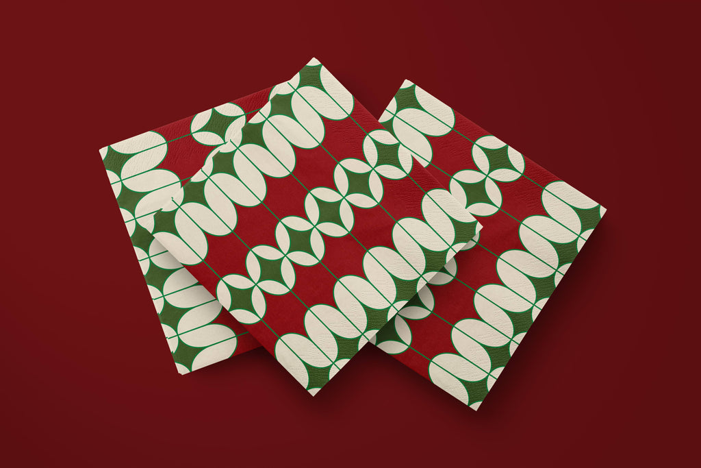Noël Mod paper napkins on a deep red ground — three napkins scattered