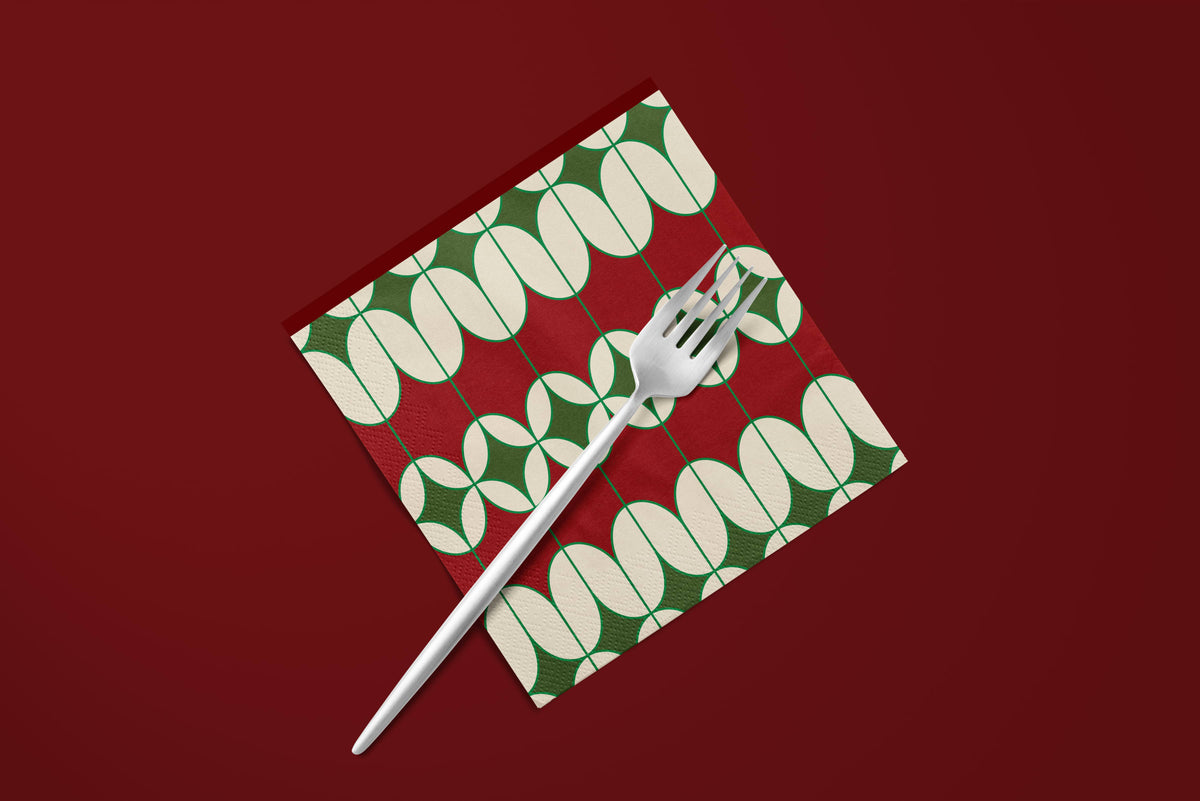 Noël Mod paper napkins on a deep red ground — a napkin with a fork