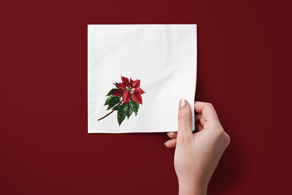 Noël Poinsettia paper napkins on a deep red ground — a napkin held in hand