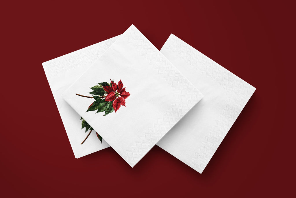 Noël Poinsettia paper napkins on a deep red ground — three napkins scattered
