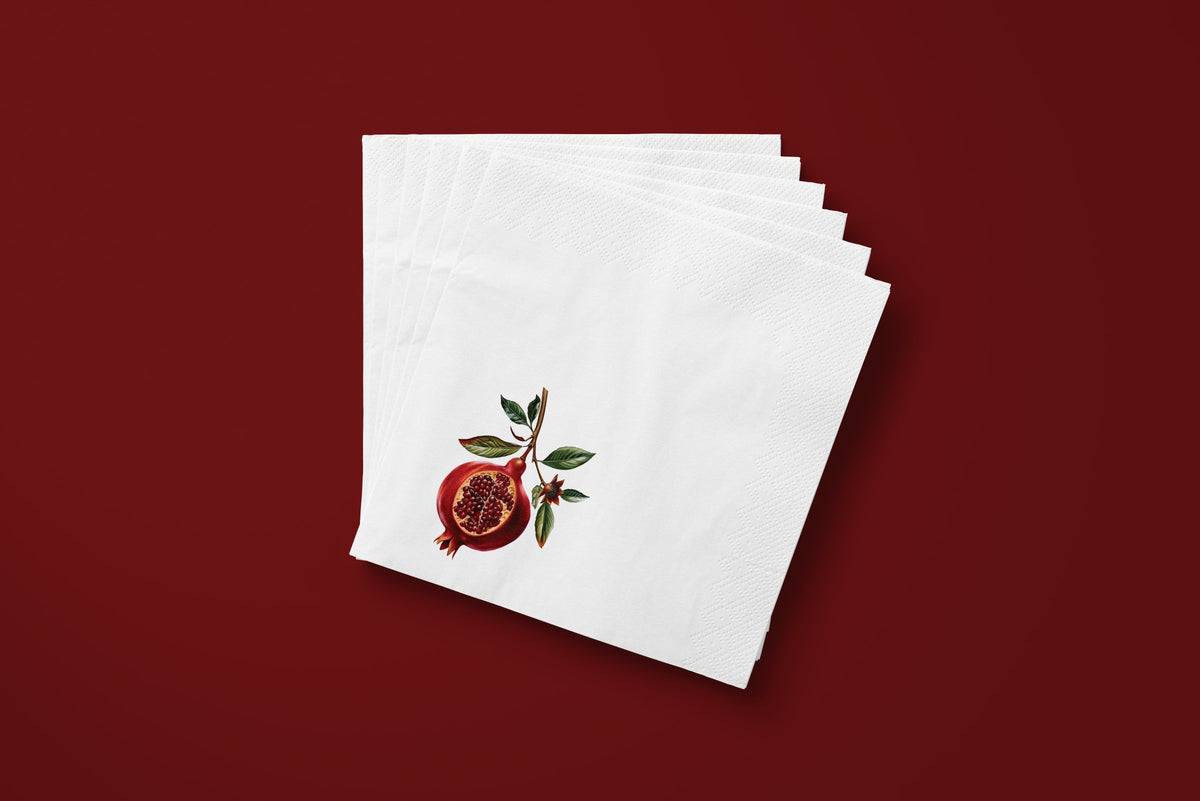 Noël Pomegranate paper napkins on a deep red ground — a fanned stack