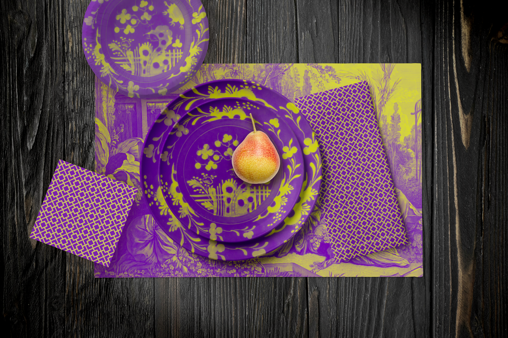 La Chinoiserie Violet Party Table — plates stacked on the garden-scene placemat with fretwork napkins, in chartreuse on magenta, on dark wood