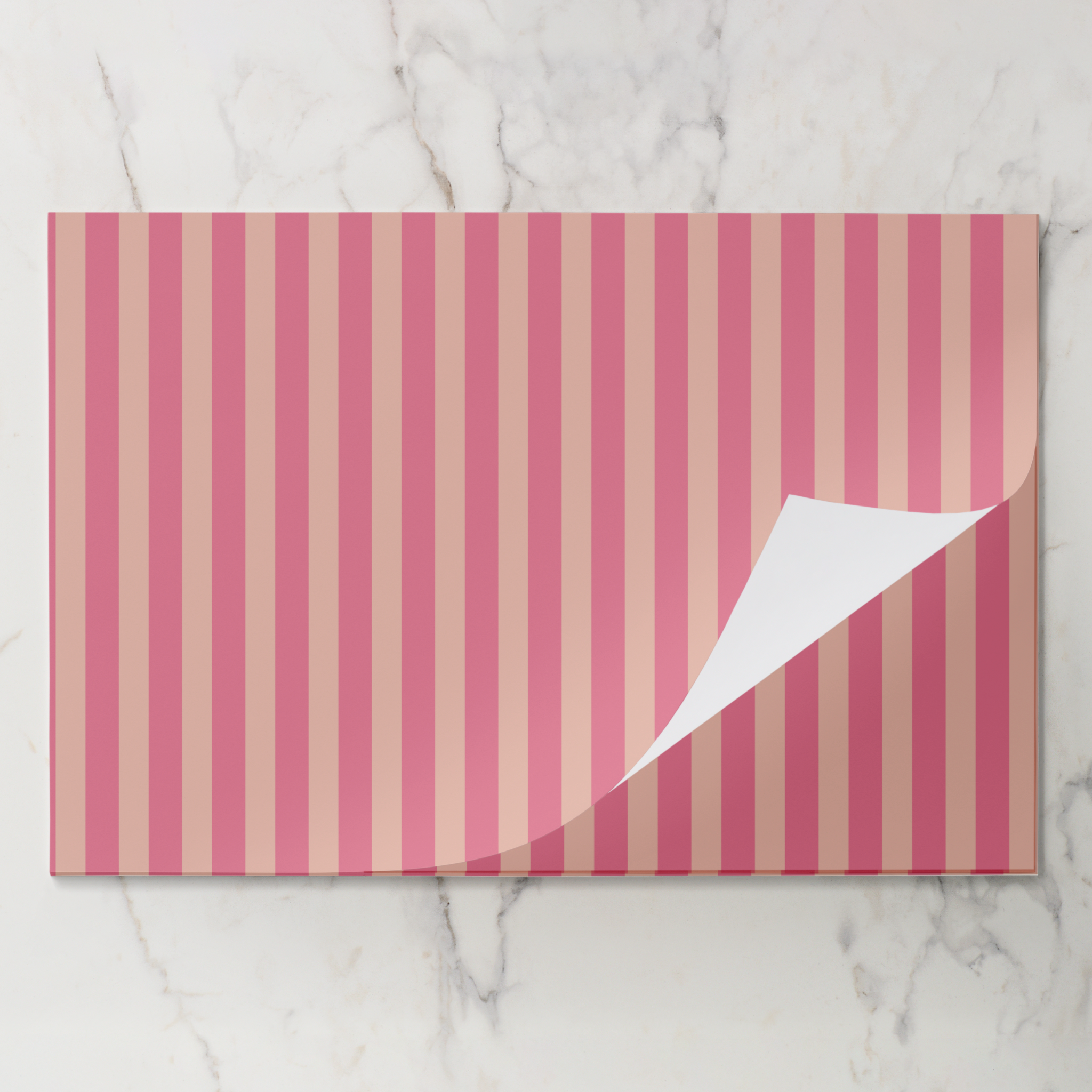 Pink and beige striped paper with a corner folded over on a marble background