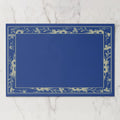 La Chinoiserie Bordure paper placemat in Cobalt — cream engraved floral border on cobalt blue, open centre