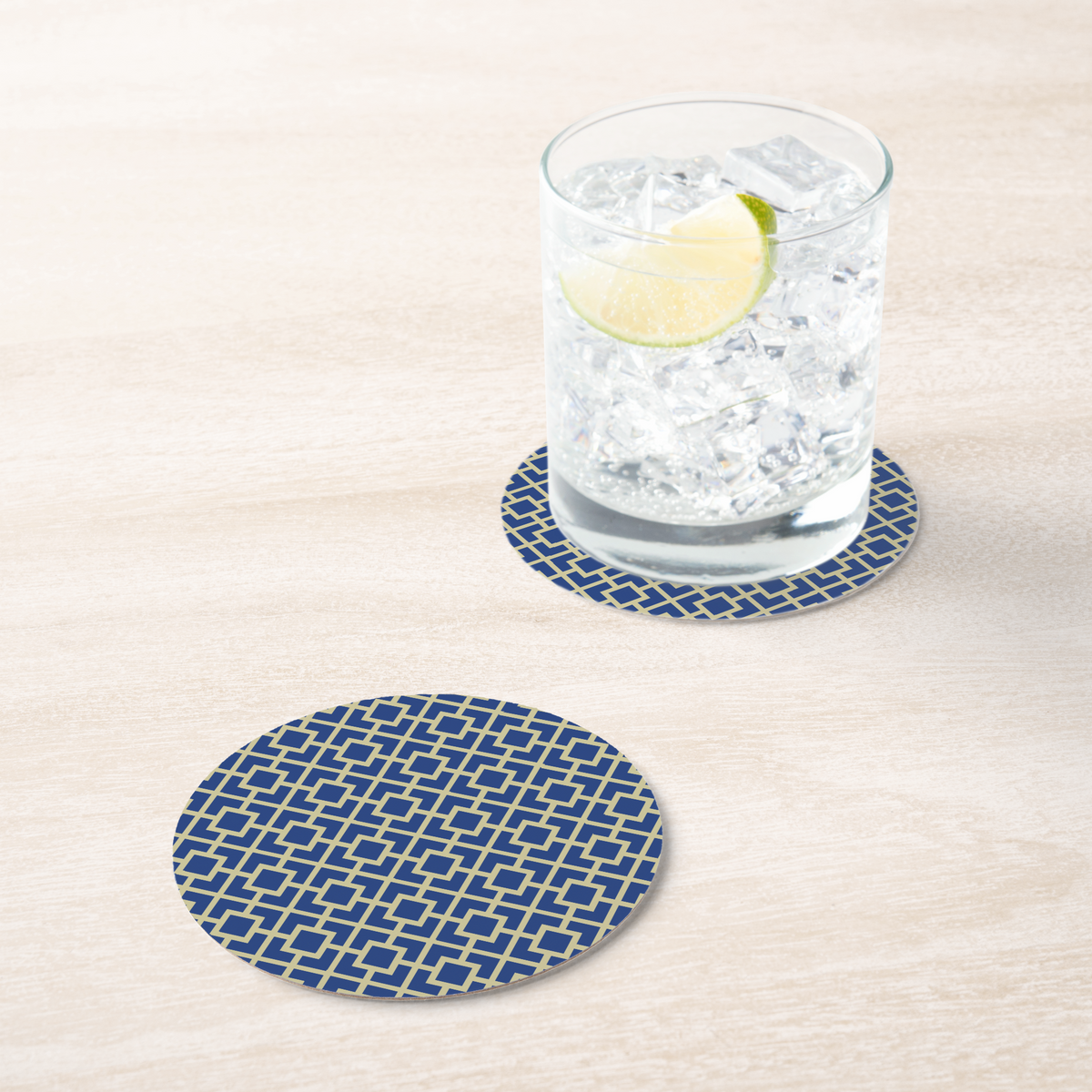 La Chinoiserie Cobalt Fretwork paper coaster under an iced drink on pale wood