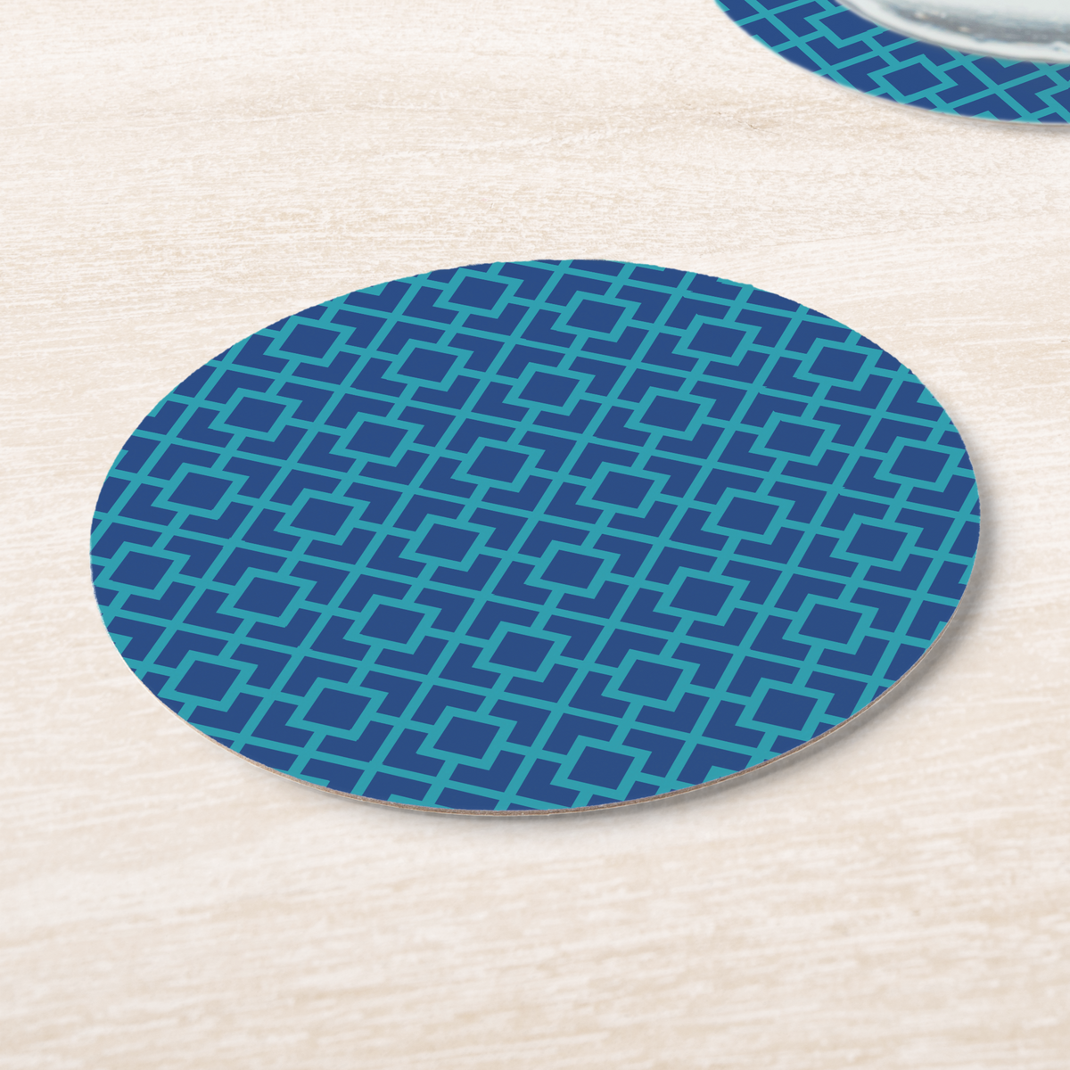 La Chinoiserie Lagoon Fretwork paper coasters on pale wood, navy lattice on teal