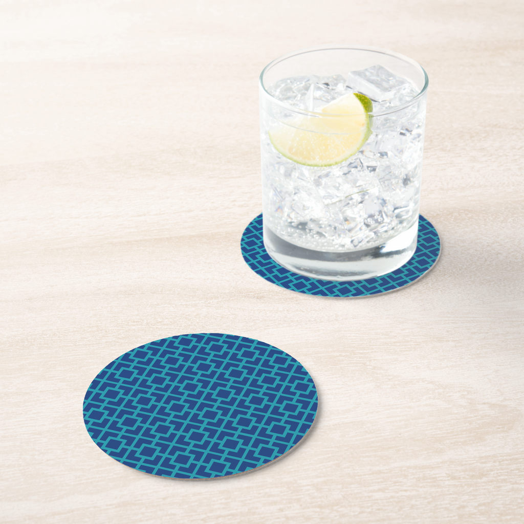 La Chinoiserie Lagoon Fretwork paper coaster under an iced drink on pale wood