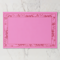 La Chinoiserie Bordure paper placemat in rouge — deep rose engraved floral border on a bright rose ground