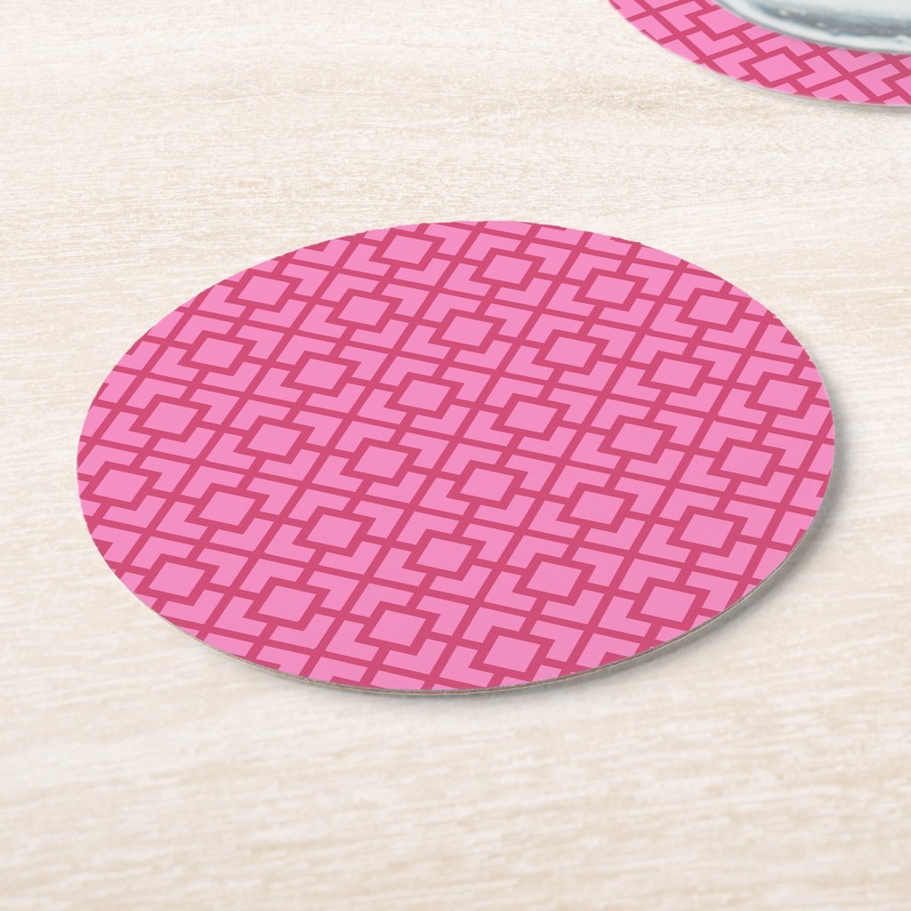 La Chinoiserie Rouge Fretwork paper coasters on pale wood, deep rose lattice on pink