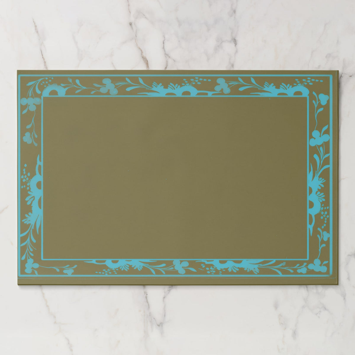 La Chinoiserie Bordure paper placemat in Teal — teal engraved floral border on olive, open centre