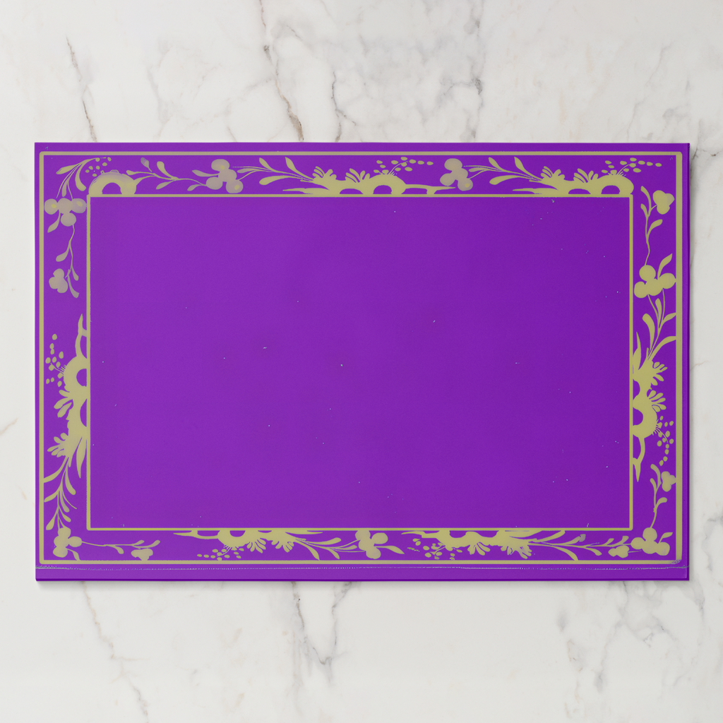 La Chinoiserie Bordure paper placemat in violet — gold engraved floral border framing an open violet centre