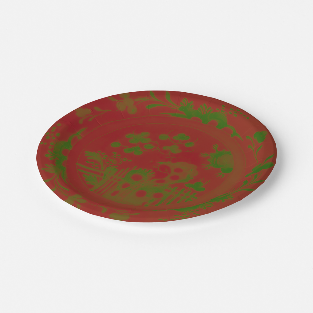 La Chinoiserie Noël paper plate tilted to show the rim — green garden scene on lacquer red