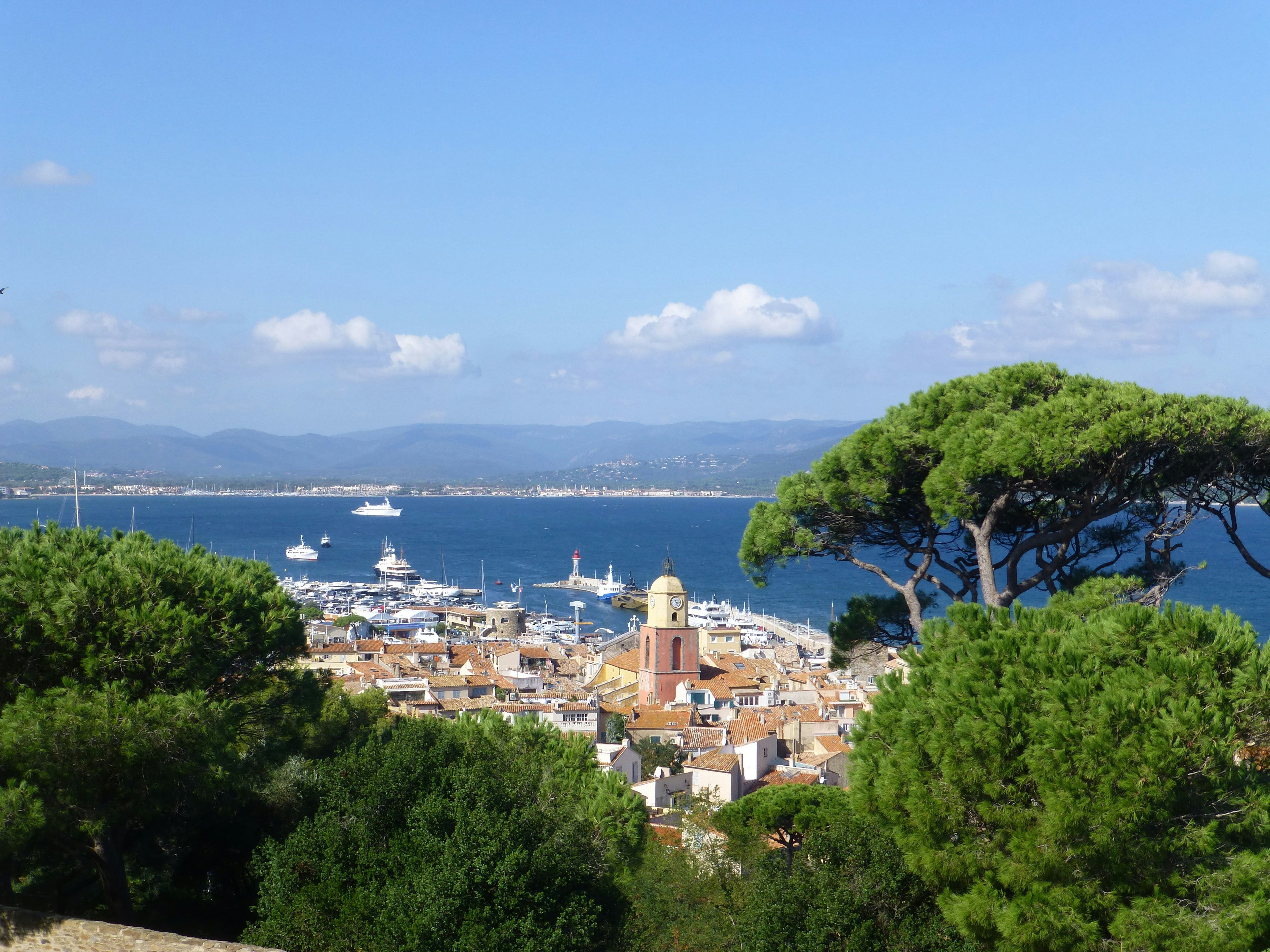 View of a coastal village on the French riveria with boats and green trees in the foreground